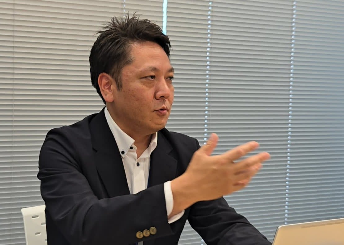 奥村氏インタビュー、手振りを交えて説明する様子